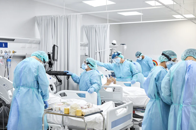 Doctors and nurses in ICU, wearing protective gowns, masks and goggles.