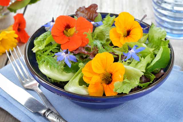 A bowl of salad with flowers.