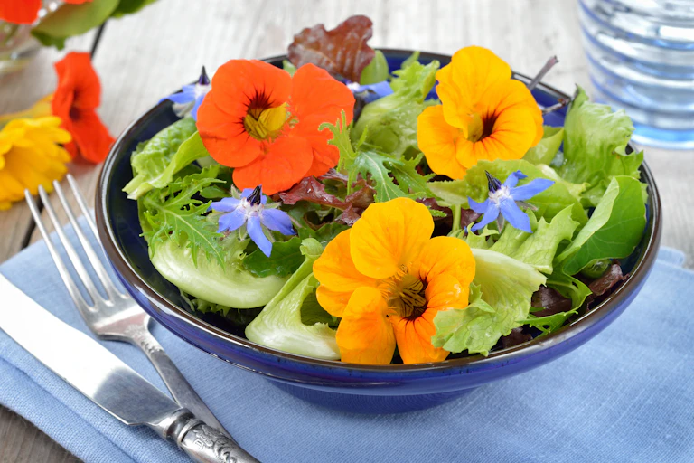A bowl of salad with flowers.