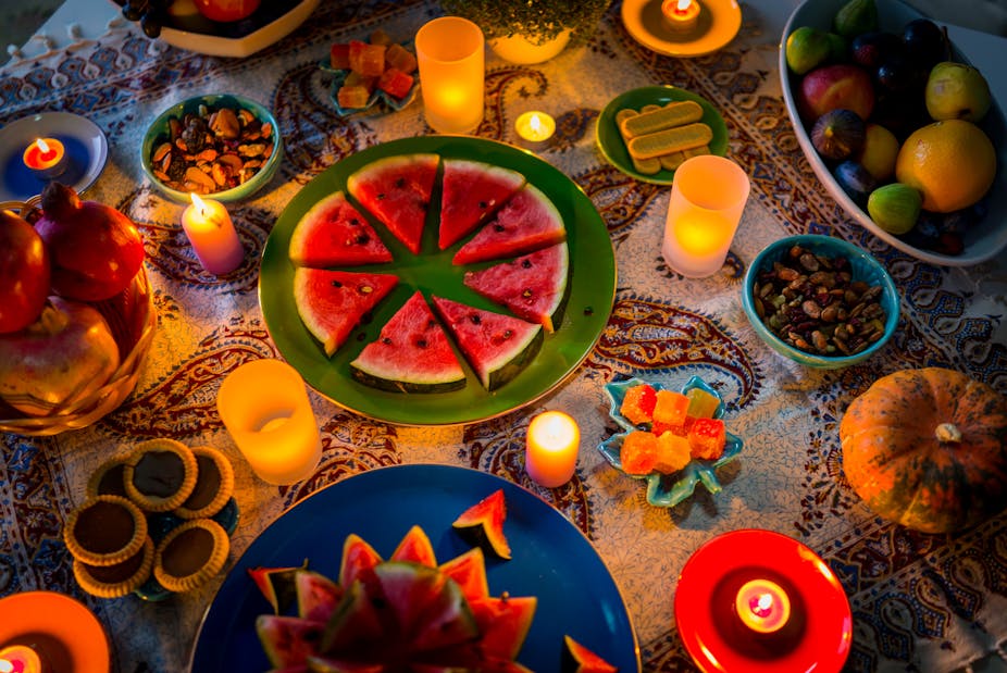 Pieces of watermelon, pomegranates and dried fruits set up on a table.