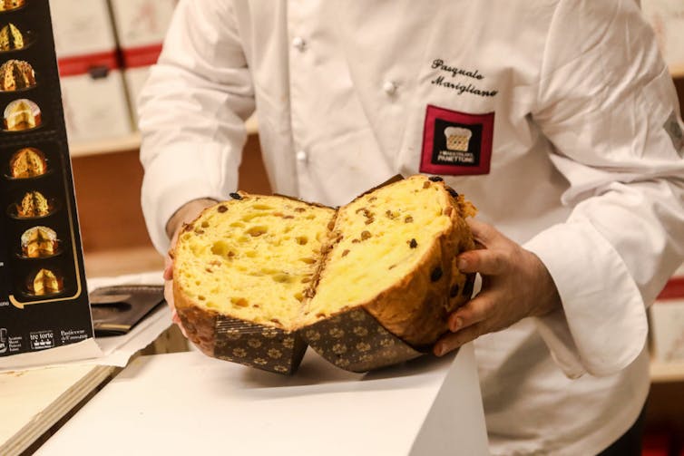 A chef holds two halves of a cake.