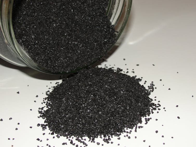 A pile of shiny black powder and a jar.