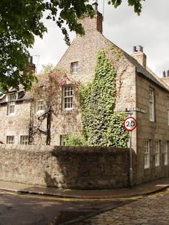 Stone house with ivy reaching up one wall to second story.