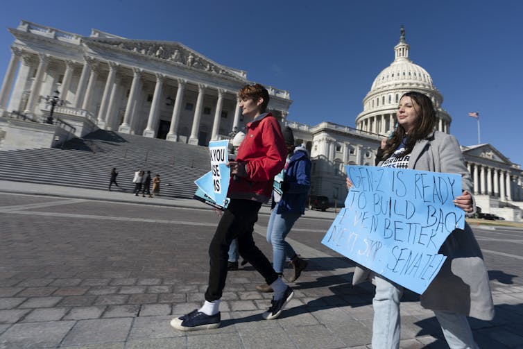 People hold signs outside the U.S. Capitol