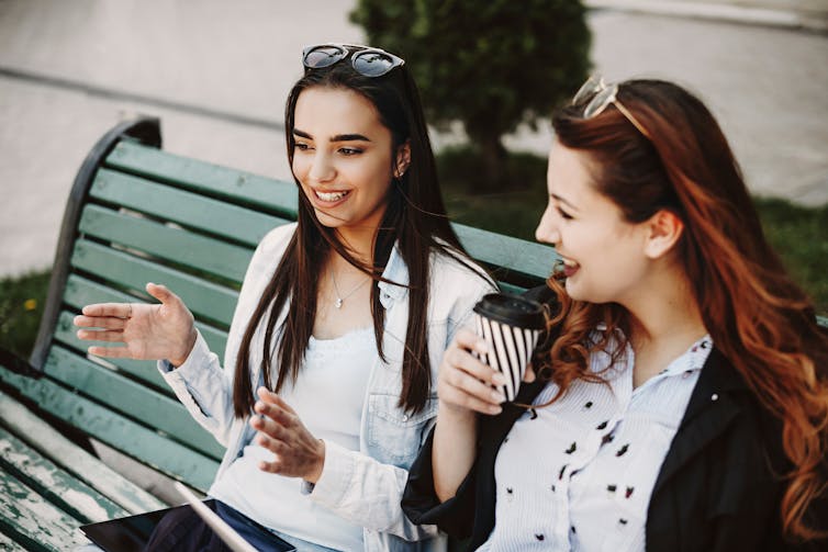 Two people talking on a bench