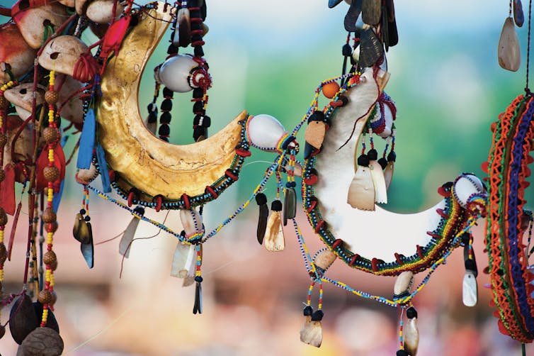 Colorful crescent-shaped objects covered in shells and strings.