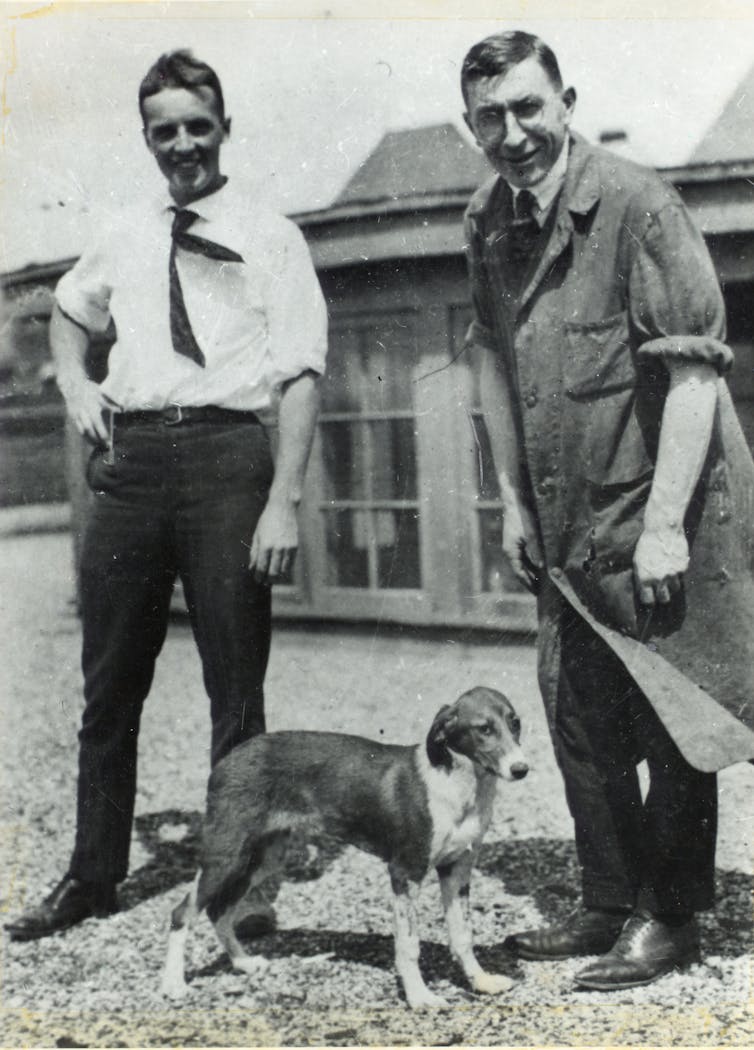Two men pose with a dog.