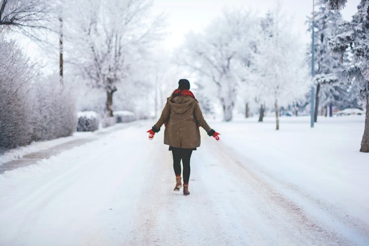 A person seen from behind walking on a snowy road