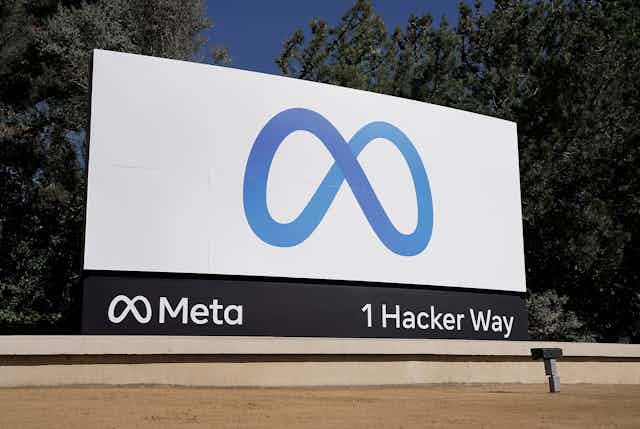 A ground-level billboard with an infinity-sign-like corporate logo