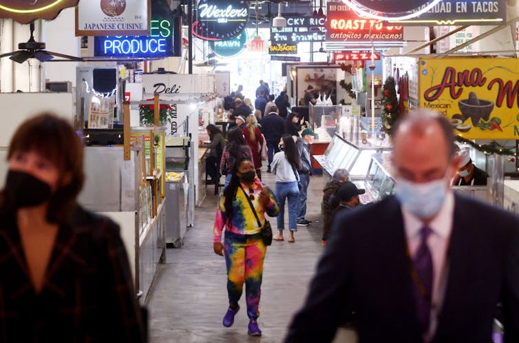 People wearing face masks inside an outdoor market.