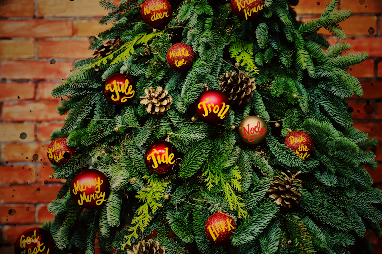 A Christmas tree with baubles covered in the words we only use at Christmas time: Yule, yuletide, Noel, Hark, Merry, God rest you