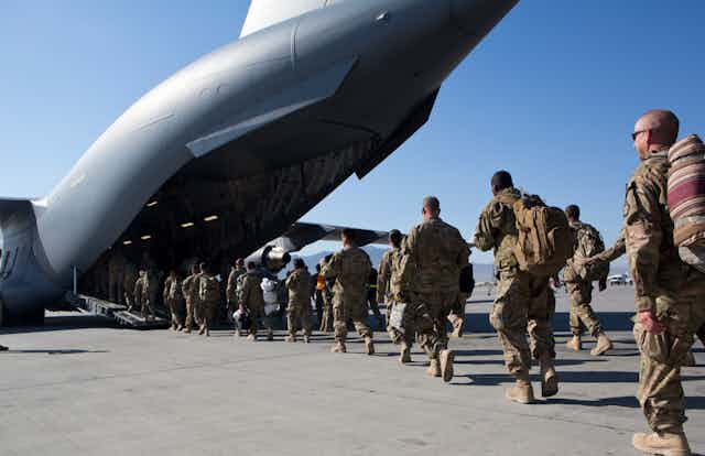 Soldiers walk into a cargo plane.