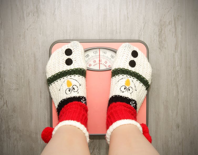 Person in festive socks standing on a bathroom scale.