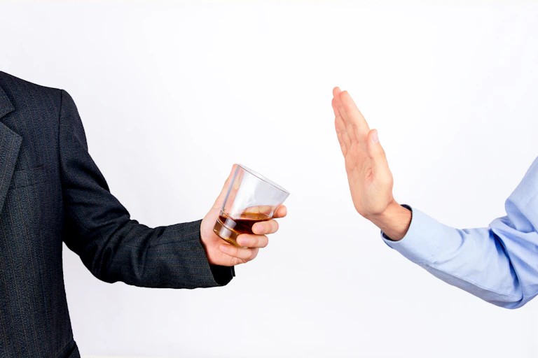 Person offering alcohol and another person declining the offer