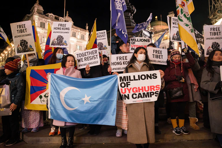 Women demontrating with banners about Chinese state oppression of Uyghurs and Tibetans.