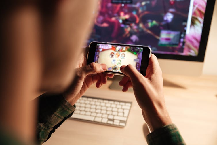 Hands playing a game on a smartphone.