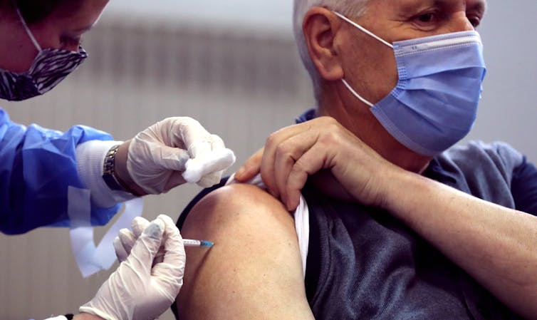 Um homem sendo vacinado contra COVID