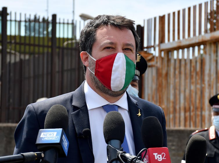 Former Italian interior minister Matteo Salvini speaks to journalists outside his trial in Catania, Sicily, wearing an Italian tricolore face mask.