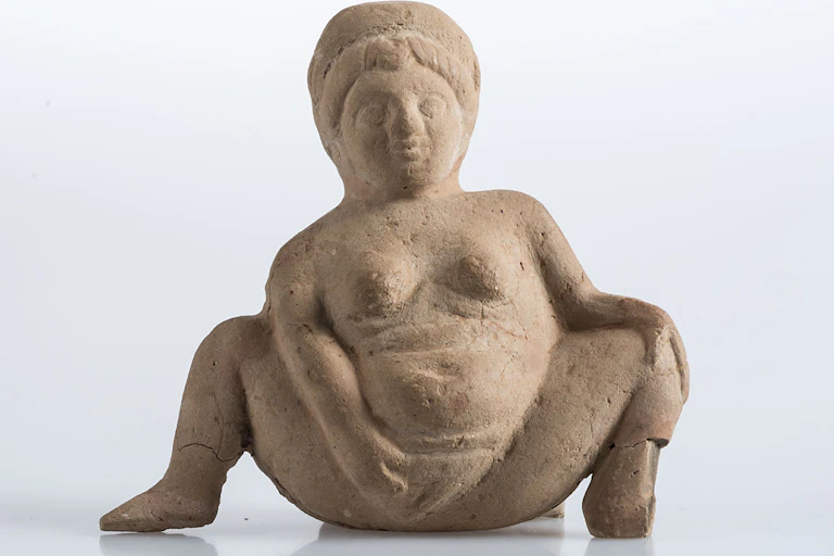 Statuette dite Baubod, une femme nue écartant les jambes et montrant sa vulve de la main droite.