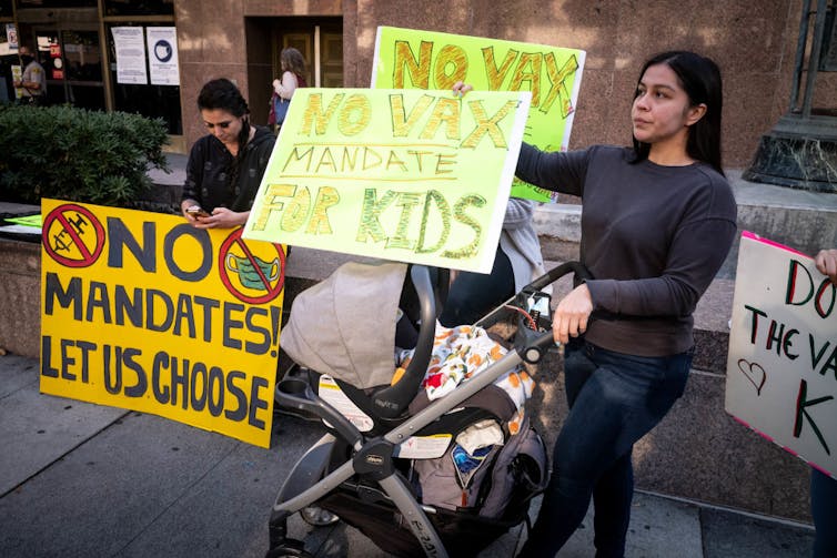 Anti-vaccine protesters holding up signs reading 'NO VAX MANDATE FOR KIDS'