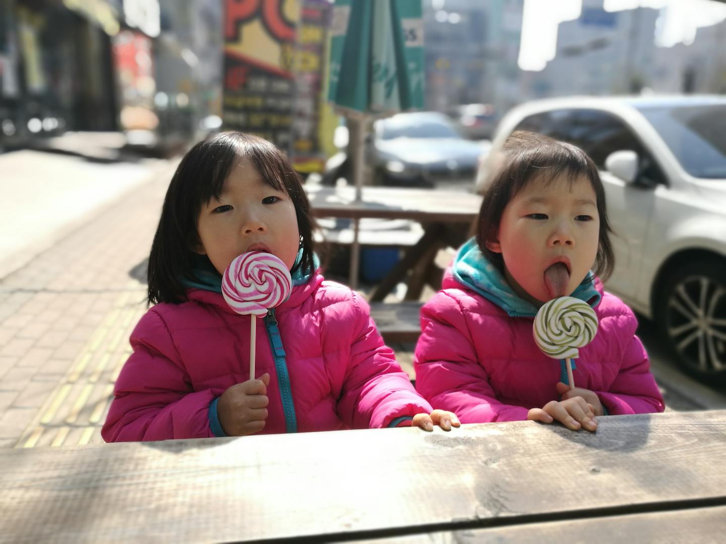 Two girls licking lollipops.