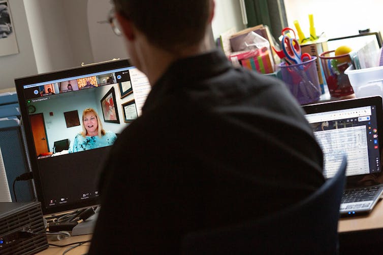A teacher is seen in a classroom on a videoconference.