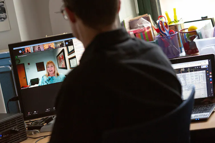 A teacher is seen in a classroom on a videoconference.