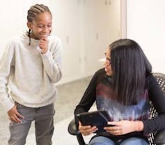 An adult shows a child a device.