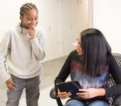 An adult shows a child a device.