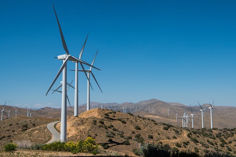 Wind turbines next to a road on a rugged ridge.
