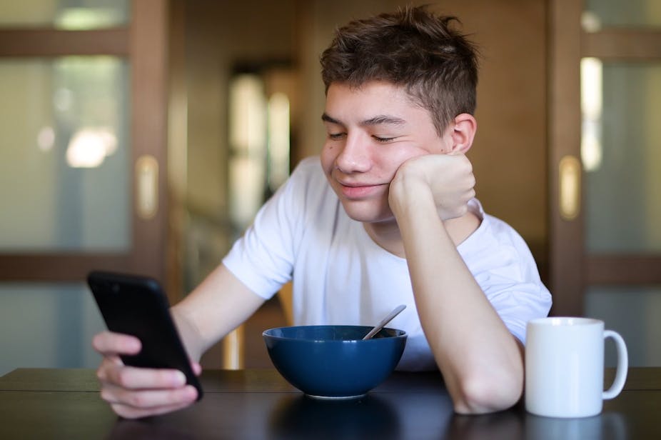 Teenager with breakfast bowl looking at phone