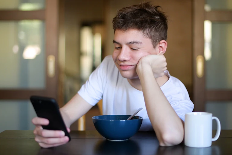 Teenager with breakfast bowl looking at phone