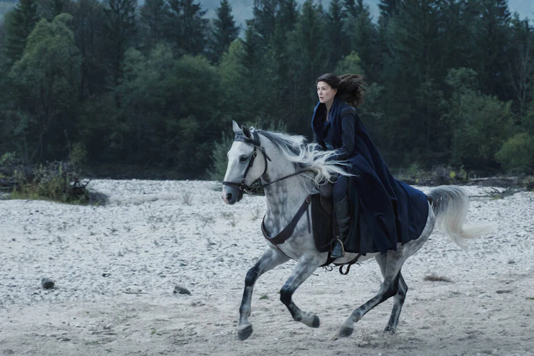 Woman in medieval clothes rides grey horse