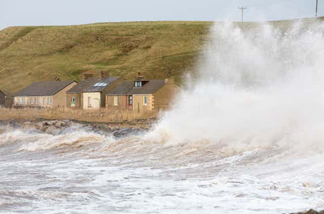 Waves crashing next to coastal homes.