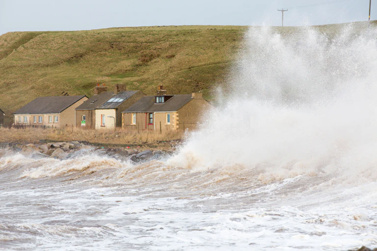 Waves crashing next to coastal homes.