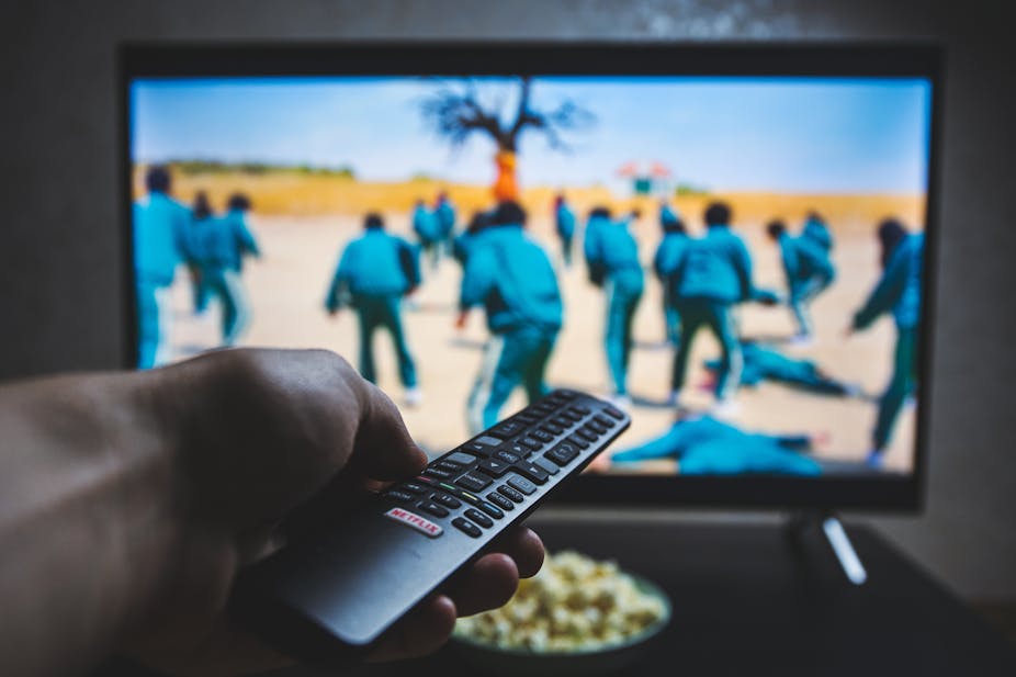 A hand holds a remote in front of a television