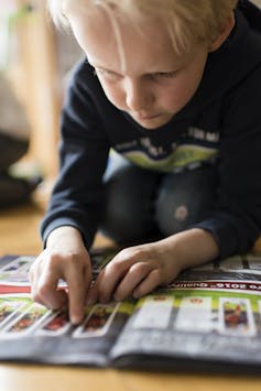 A boy places a trading card in a binder.
