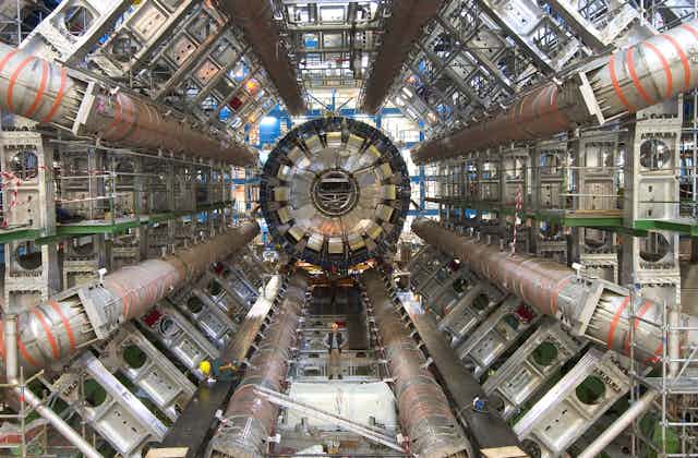 Inside of a large tube full of pipes and technical equipment.
