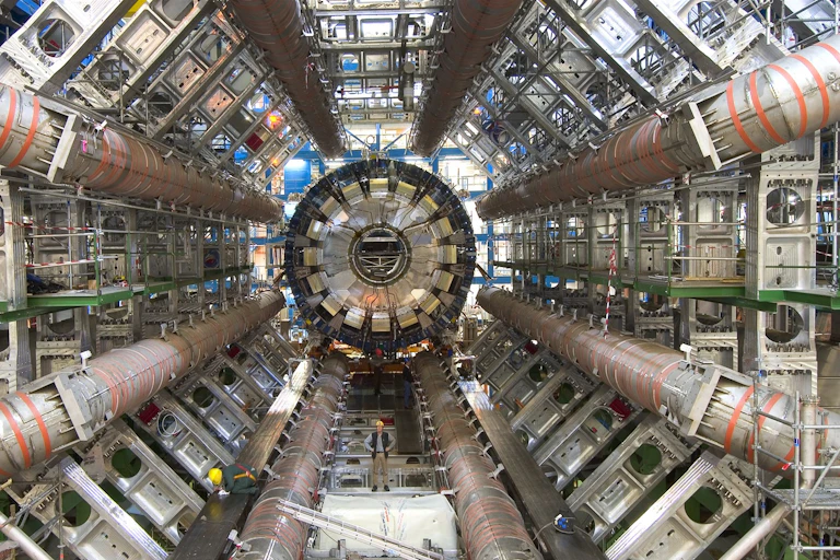 Inside of a large tube full of pipes and technical equipment.