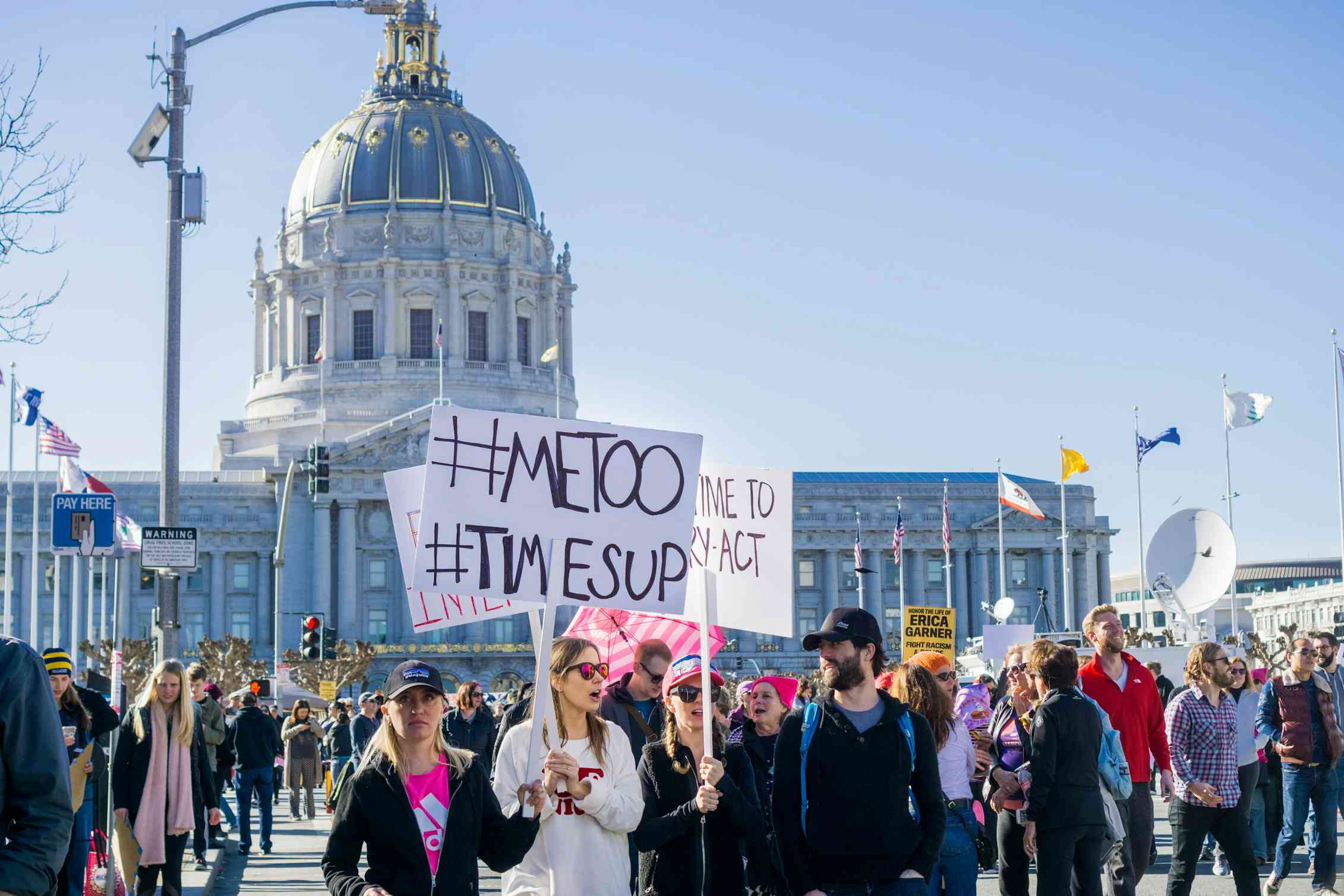 A protest photo, people carry signs reading '#MeToo #TimesUp'