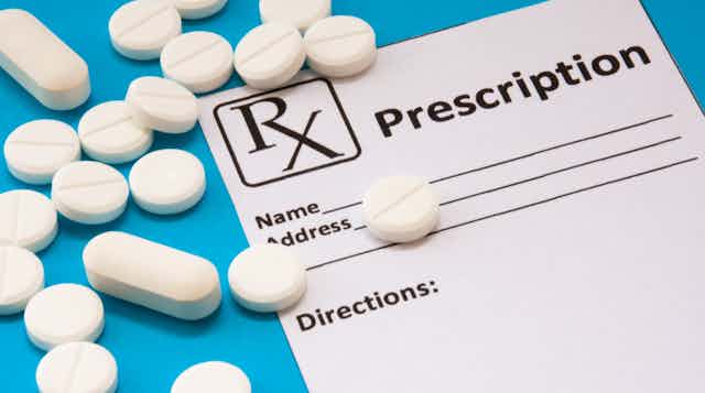 A prescription pad and white tablets against a blue background