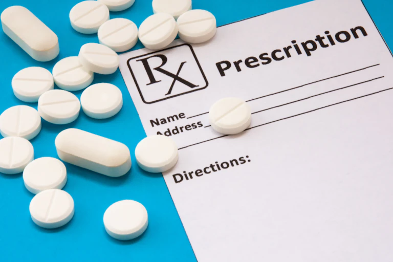A prescription pad and white tablets against a blue background
