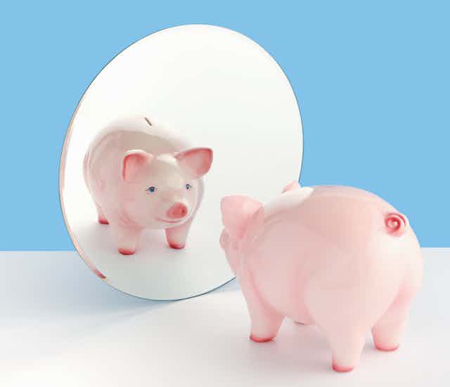 A piggy bank gazes into a mirror and sees its own reflection