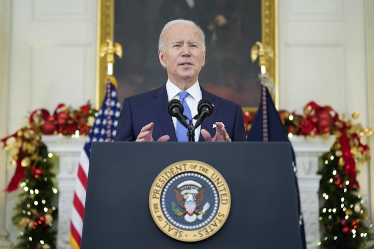 A man stands behind a podium with a crest that says 'Seal of the President of the United States'