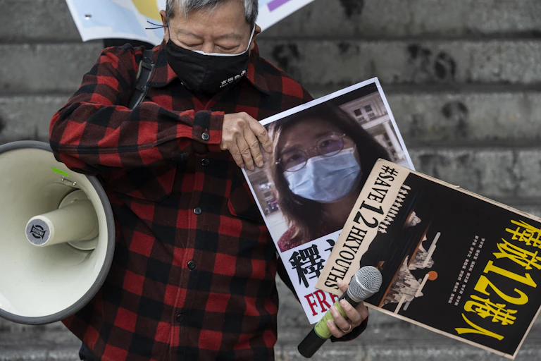A Chinese man carrying a megaphone and posters calling for the release of journalist Zhang Zhan and other political prisoners.