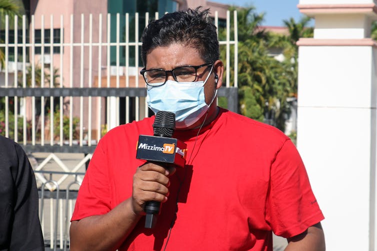 Myanmar journalist Than Htike Aung, wearing a COVID mask, reporting from the Union Election Commission in Naypyidaw, Myanmar, after the eleciton in December 2020.