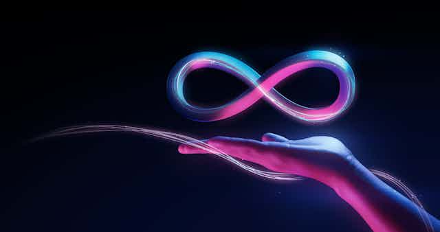 A woman's hand with the infinity sign floatiing above it, to represent the metaverse.