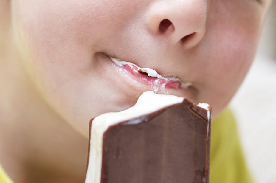 Close-up of nose and mouth of a kid eating an ice cream sandwich.