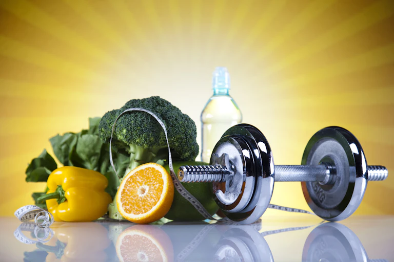 A silver dumbbell with a bottle of water and healthy foods