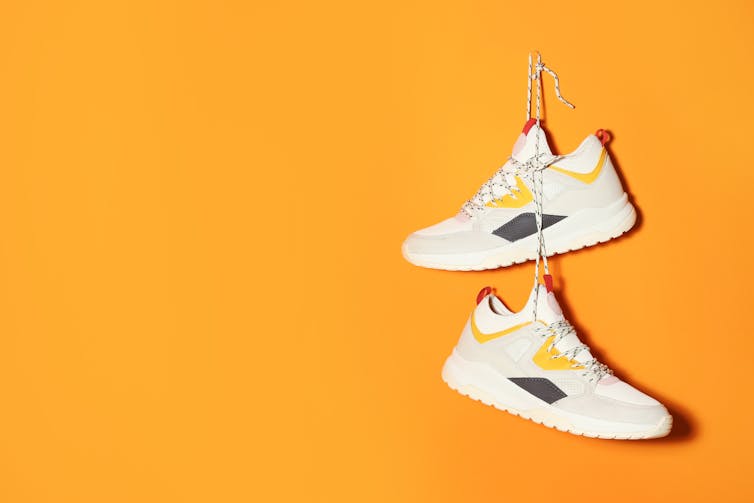 A pair of sneakers hanging against a yellow background